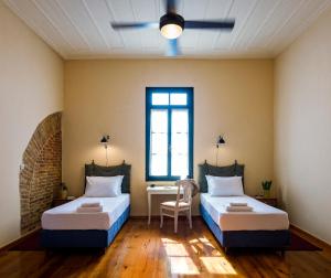 two beds in a room with a desk and a window at Sundial Lodge in Chania