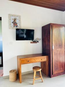 a wooden desk with a tv and a stool at Canting Bali Suite in Ubud