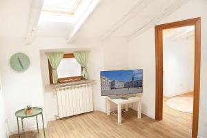 a white living room with a tv and a table at La mansardina in Trieste