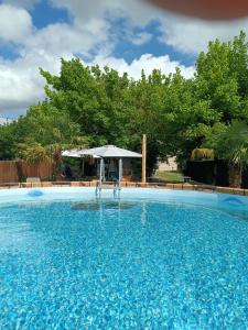 a large blue swimming pool with an umbrella at La casa di Mary in Castiglion Fiorentino