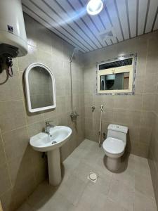 a bathroom with a sink and a toilet and a mirror at نجوم السعد 6 in Al Masfalah