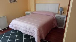 a bedroom with a large bed with a pink blanket at Apartamento vacacional en Cariño in Cariño