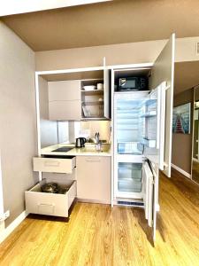 a small kitchen with white cabinets and an open refrigerator at Sunshine Apartments Batumi in Batumi