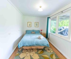 a bedroom with a bed with a blue blanket and a window at Havehus in Denmark