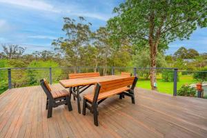 a wooden table and two benches on a wooden deck at Havehus in Denmark