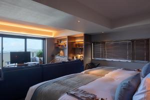 a bedroom with a bed and a couch and a television at Glamday Style Okinawa Yomitan Hotel & Resort in Yomitan