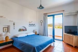 a bedroom with a blue bed and a sliding glass door at Villa Costa Haraki in Haraki