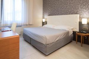 a bedroom with a large bed and a desk at Astra Hotel in Ferrara