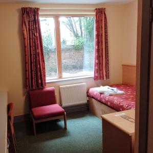 a room with a bed and a chair and a window at St John's College in Durham