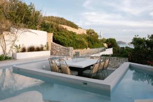 a patio with a table and chairs next to a swimming pool at Paros Agnanti Resort & Spa in Parikia