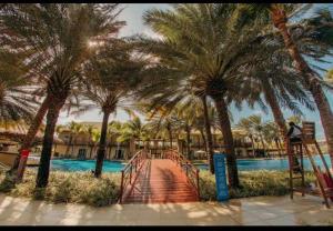 einen Fußweg, der zu einem Pool mit Palmen führt in der Unterkunft Golf Ville Residence Resort, apartamento 3 suítes, 110m2, Porto das Dunas próx ao Beach Park in Aquiraz