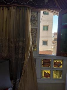 a window in a room with a curtain and a building at منزل السعاده in Aswan