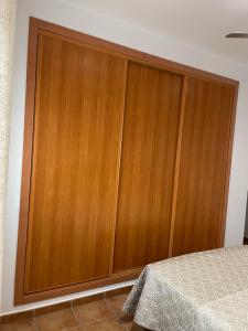 a large wooden closet in a bedroom with a bed at Piso Abril in Zafra