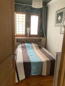 a bedroom with a bed in a room with two windows at Appartement à côté de la Gare in Hendaye