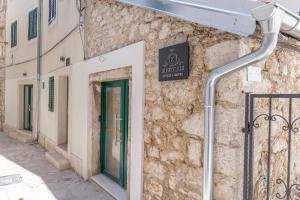 a building with a green door and a sign on it at X Boutique Marinac Studio Apartments & Rooms in Šibenik