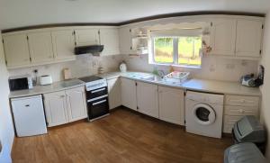 a kitchen with white cabinets and a sink and a dishwasher at Green Acres Self Catering in Claremorris