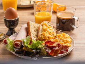 a plate of breakfast food on a table with orange juice at ibis Bordeaux Centre - Gare Saint-Jean in Bordeaux