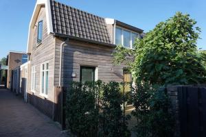 a wooden house with a black roof on a street at Have a nice stay! - De Pottenbakkerij in Noordwijk