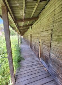 a wooden walkway under a wooden building at Fish and sleep - lake house in Alūksne
