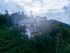 ein weißes Haus auf einem Hügel mit Bäumen in der Unterkunft Udaya Hills Cottages in Vagamon