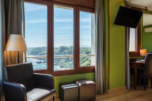 Una habitación con una silla y un escritorio y una ventana. en La Colina, en Gijón