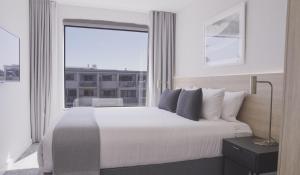 a bedroom with a large bed with a large window at Quest Mt Maunganui in Mount Maunganui