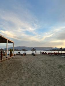 a beach with chairs and umbrellas and the ocean at Vila Roan in Vlorë