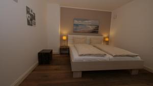 ein Schlafzimmer mit einem Bett mit zwei Lampen in der Unterkunft Landhaus Strandhafer HT 1 in Wenningstedt-Braderup