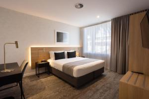 Una habitación de hotel con una cama, un escritorio y una ventana. en Quest Mt Maunganui, en Mount Maunganui