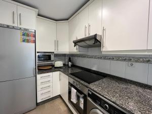 a kitchen with white cabinets and granite counter tops at Puerto Marina in Benalmádena