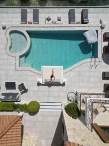 a woman sitting on a couch next to a swimming pool at Emerald Villas & Suites - The Finest Hotels Of The World in Agios Nikolaos