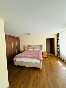 a bedroom with a large bed and a wooden floor at Rožu namu apartamenti in Kuldīga