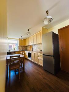 a kitchen with a stainless steel refrigerator and a table at Rožu namu apartamenti in Kuldīga