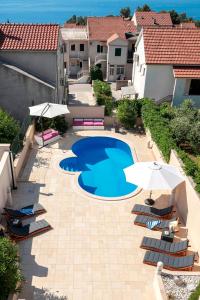 an overhead view of a swimming pool with chairs and umbrellas at Hektorovic poolside apartments in Bol