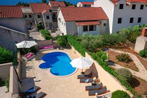 an overhead view of a swimming pool with chairs and an umbrella at Hektorovic poolside apartments in Bol