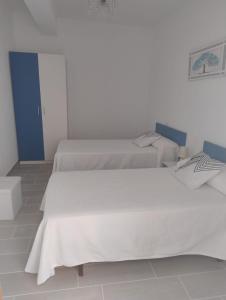 a white room with two beds in it at Apartamento Lago Pereira in Muxia +1 photo