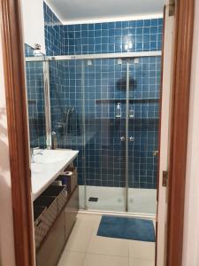 a blue tiled bathroom with a shower and a sink at Best of nature 2, Matosinhos beach, PortoCityParc Metro! in Matosinhos