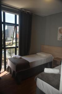 una camera con due letti e una grande finestra di Unity Hotel - Vila Mariana SP a San Paolo