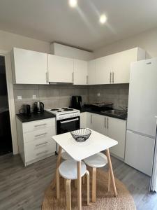 a kitchen with white cabinets and a white table and chairs at Rouli's Houses by All About Paxos in Oziás