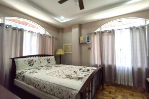 a bedroom with a bed and two large windows at Tampus Staycation Rental Cebu in Bulacao