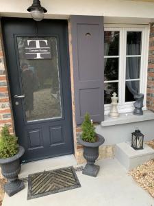 a black door on a house with two potted plants at Hébergement à Everly in Éverly