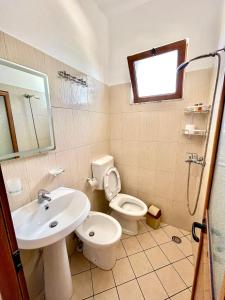 Un baño con lavabo, inodoro y ducha. en Xhou's Home, en Shkodër