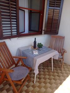 a table with two chairs and a bottle of wine on it at Apartment Studio Antonia in Medulin +16 photos
