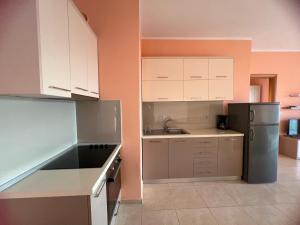 a kitchen with white cabinets and a black refrigerator at Horizon Apartments - Sea & Mountain View -Modern & Spacious Stay in Orikum