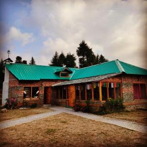 a brick house with a green roof and a yard at Wild orchid trail cottages in Jhatingr