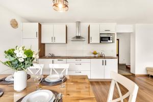 a kitchen with white cabinets and a table with chairs at Apartments Svetina in Bled