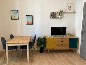 ein Esszimmer mit einem Tisch und einem Schreibtisch mit einem TV in der Unterkunft Grand T2 43m2 plages du Mourillon in Toulon