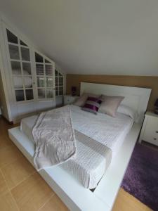 a white bedroom with a large white bed with pillows at Tejas verdes in Argoños +6 photos