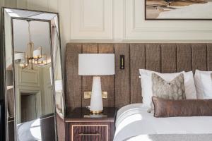 a bedroom with a bed with a mirror and a lamp at Dunkeld House Hotel in Dunkeld