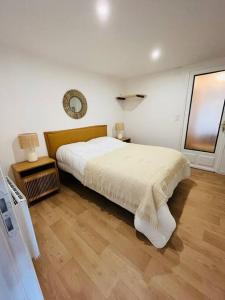 a white bedroom with a bed and a window at Appartement Le Romy Vue Montagne in Mont-Dore